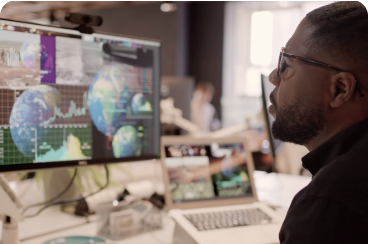 A man wearing glasses looks at a computer monitor and reviews data.